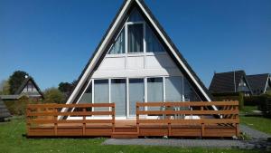 ein dreieckiges Haus mit zwei Bänken im Gras in der Unterkunft Nurdachhaus 128 Ferienpark Fedderwardersiel in Butjadingen