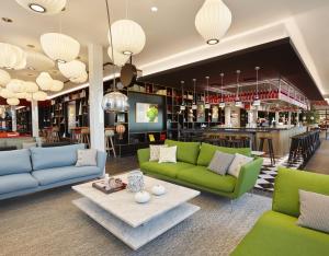 a living room with green couches and a bar at citizenM Copenhagen Radhuspladsen in Copenhagen