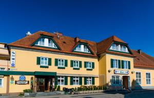 ein großes gelbes Gebäude mit braunem Dach in der Unterkunft Hotel Pendl in Kalsdorf bei Graz