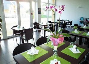 a restaurant with tables and chairs with flowers on the table at Le Fleur"H"on 11 d'Honfleur, T2 en Résidence avec Piscine, WIFI et Parking gratuits in Équemauville