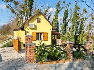 a small yellow house with a brick fence at Rustic Holiday Home in Donja Stubica with Terrace in Donja Stubica