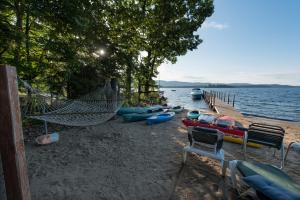 a hammock and kayaks on a beach next to the water at The Juliana Resort in Lake George