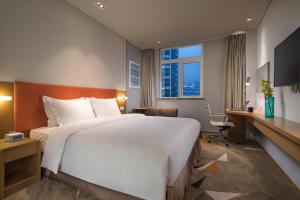 een hotelkamer met een groot bed en een bureau bij Holiday Inn Express Suzhou New District, an IHG Hotel in Suzhou