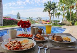 a table topped with plates of breakfast food next to a pool at Hotel Lindo Ajijic Bed & Breakfast in Ajijic