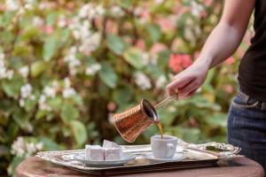 a person pouring coffee into a cup on a table at Nafsimedon Hotel in Nafplio