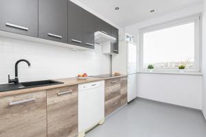 a kitchen with wooden cabinets and a sink and a window at Rooms4Less in Gdańsk