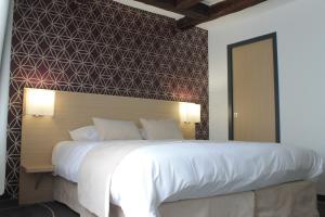 una camera da letto con un grande letto bianco con una parete a motivi geometrici di Hôtel Le Blason a Amboise