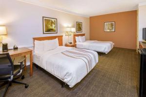 a hotel room with two beds and a desk at La Quinta Inn by Wyndham San Antonio Market Square in San Antonio