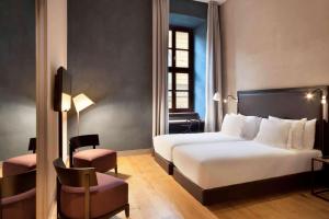 ein Hotelzimmer mit einem Bett und einem Stuhl in der Unterkunft NH Collection Torino Piazza Carlina in Turin