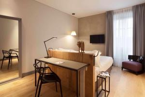 a hotel room with a bed and a table and chairs at NH Collection Torino Piazza Carlina in Turin