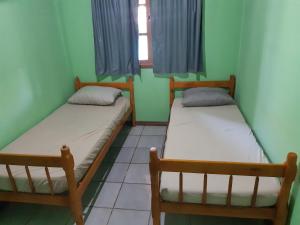 2 camas en una habitación con paredes verdes y ventana en JOÃO CARLOS CASAS 3 Quartos Penha SC, en Penha