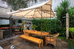 Brazilodge All Suites Hostel في ساو باولو: طاولة وكراسي خشبية تحت مظلة على الفناء