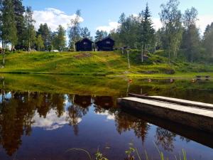 um reflexo de uma cabana num lago em Groven Camping & Hyttegrend em Åmot