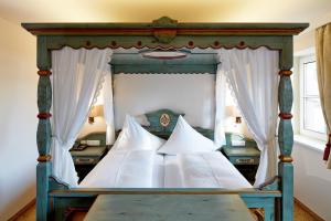 a bedroom with a canopy bed with white pillows at Hotel Flatscher in Stuhlfelden