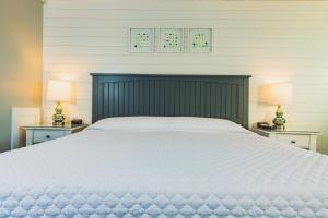 a bedroom with a large white bed with two lamps at Bearskin Neck Motor Lodge in Rockport