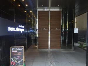 a door to a building with a sign in front of it at Dormy Inn Kagoshima in Kagoshima