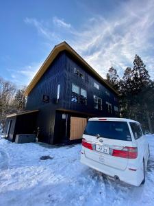 a car parked in the snow in front of a building at ZEN CHALETS Hakuba in Hakuba
