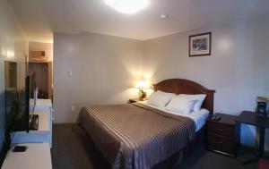 Habitación de hotel con cama, lámpara y TV en Ranchland Villa Motel, en Merritt