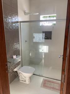 a bathroom with a toilet and a glass shower at Casa com piscina em c vermelha in Porto Seguro +1 photo