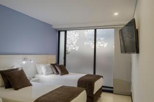 Cette chambre comprend deux lits et une télévision. dans l'établissement Hotel Regency Boutique La Feria, à Bogotá