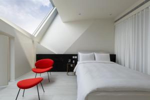 1 dormitorio con 1 cama y 2 sillas rojas en The Place Taichung, en Taichung