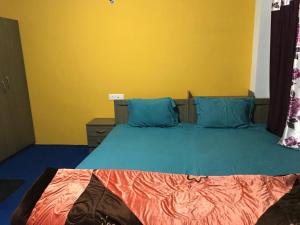 a bedroom with a blue bed with a yellow wall at Vamoose Den in Gangtok +3 photos