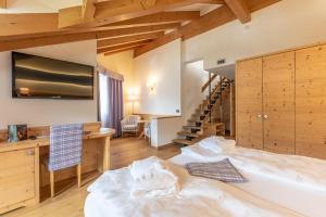 a bedroom with a bed and a desk and a staircase at Alpholiday Dolomiti Wellness & Family Hotel in Dimaro +22 photos