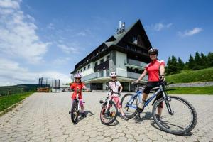 three people on bikes in front of a building at Horský Hotel Friesovy Boudy in Strážné