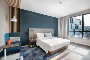 a bedroom with a bed and a blue wall at Holiday Inn Express Hangzhou Xixi Tourism Zone by IHG in Hangzhou