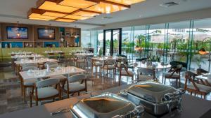 a dining room with tables and chairs and windows at Holiday Inn & Suites - Merida La Isla by IHG in Mérida