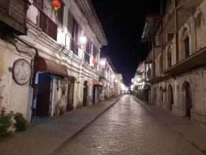 een geplaveide straat 's nachts met gebouwen en verlichting bij Escolta's Homey Lodge in Vigan