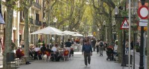 a crowd of people walking down a street with tables and chairs at Cozy Apartment Near The Beach in Barcelona