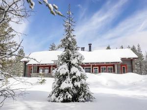 een met sneeuw bedekte kerstboom voor een huis bij Holiday Home Lustola a by Interhome in Luosto