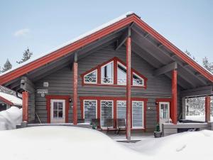 uma cabana de madeira com um telhado vermelho na neve em Holiday Home Kerkänperä by Interhome em Luosto