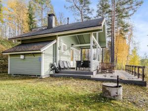 a small green house with a porch and chairs at Holiday Home Pentintupa by Interhome in Muljakkala