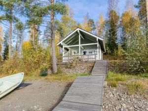 a house with a boardwalk and a boat in the woods at Holiday Home Pentintupa by Interhome in Muljakkala