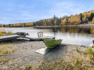 a green boat sitting on the shore of a lake at Holiday Home Pentintupa by Interhome in Muljakkala