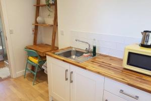 a kitchen with a sink and a microwave at Cosy, self contained annex in Cambridge