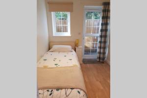 two beds in a room with a window at Cosy, self contained annex in Cambridge