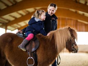 Eine Frau und ein kleines Mädchen reiten auf einem Pferd in der Unterkunft Landhaus Schulte-Göbel in Schmallenberg