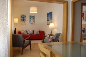 uma sala de estar com um sofá vermelho e cadeiras em Apartamentos Mare em Nazaré