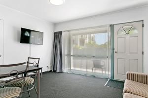 Habitación con puerta, mesa y sillas en Great Lake Motel Taupo en Taupo