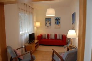 een woonkamer met een rode bank en een tv bij Apartamentos Mare in Nazaré