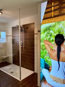 una mujer está sentada en una ducha en un baño en Landhaus Laugele Ferienwohnungen, en Nußdorf