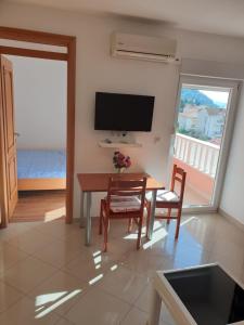 ein Wohnzimmer mit einem Tisch, Stühlen und einem TV in der Unterkunft Apartments Knezović in Gradac