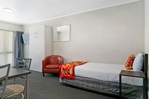 een hotelkamer met een bed en een rode stoel bij Great Lake Motel Taupo in Taupo