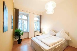 a bedroom with a white bed with a potted plant at Altbauwohnung direkt an der Karli mit Balkon - Netflix inklusive in Leipzig