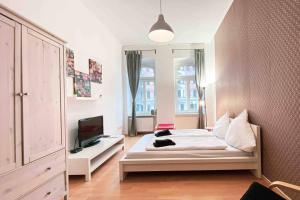 ein Schlafzimmer mit einem Bett und einem TV in der Unterkunft Altbau-Schmuckstück an der Karli mit riesigem Balkon in Leipzig