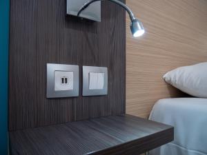 1 dormitorio con 1 cama y una luz en la pared en Contact Hotel Restaurant Bleu France - Eragny Cergy, en Éragny