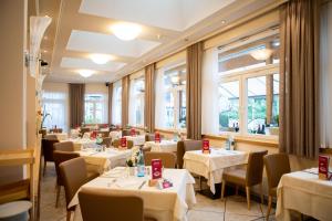 een restaurant met witte tafels, stoelen en ramen bij Hotel Union in Dobbiaco